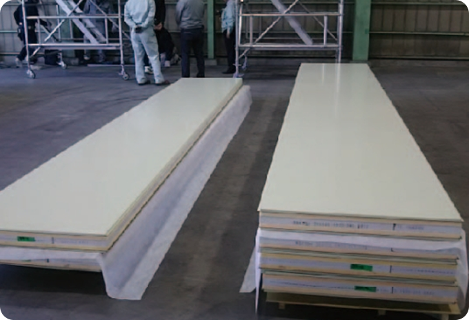 Stacks of long SN Panels on a factory floor being prepared for installation, showing the protective wrapping and the foam core layers.